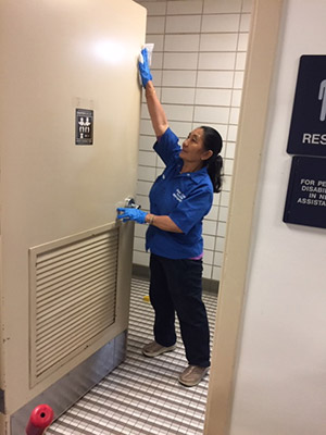 A facilities employee cleans a door